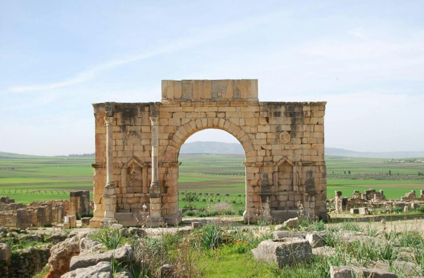 A stone arch in the middle of a field